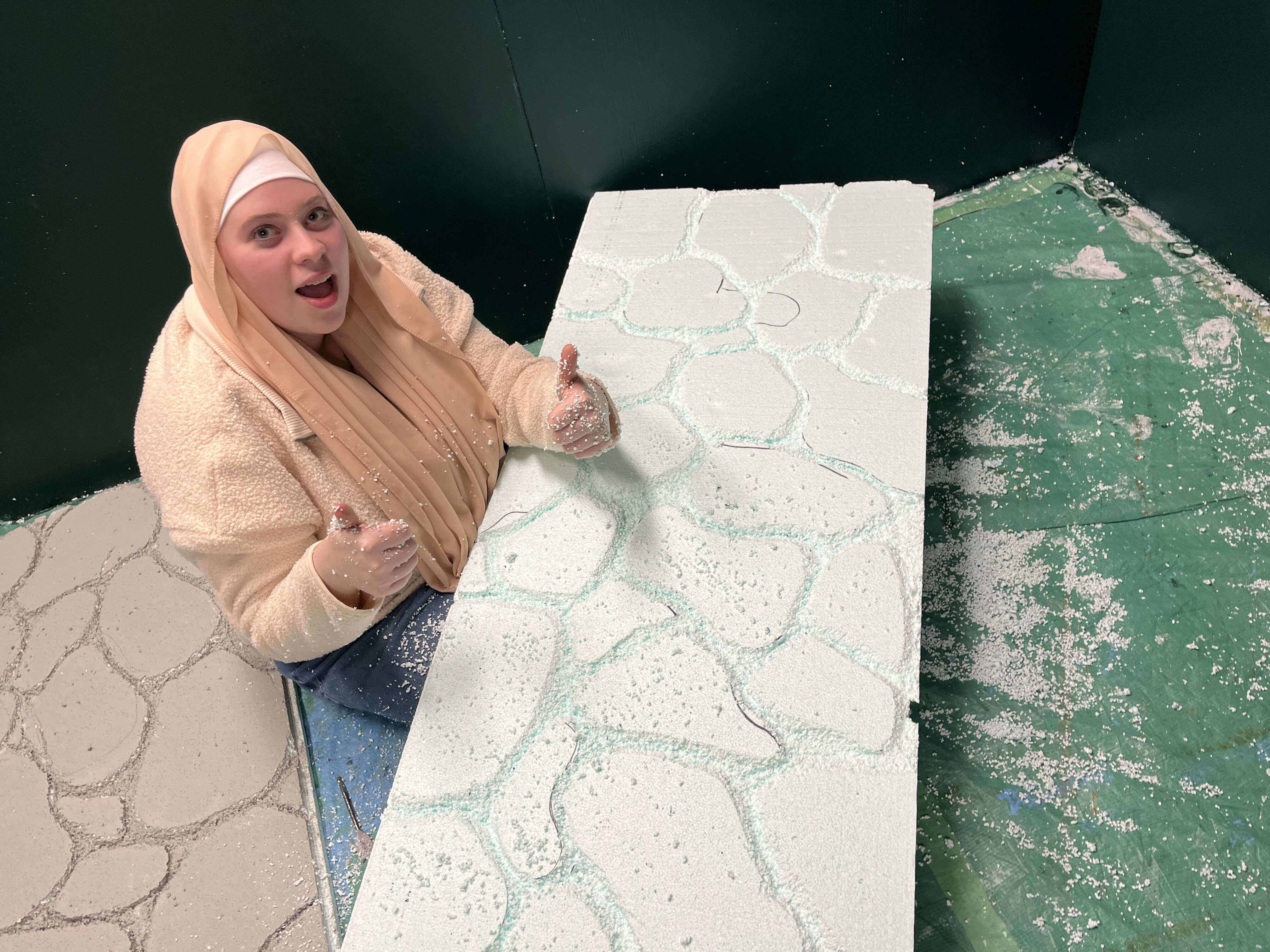 Un membre de l'équipe sculptant le mur du kiosque.