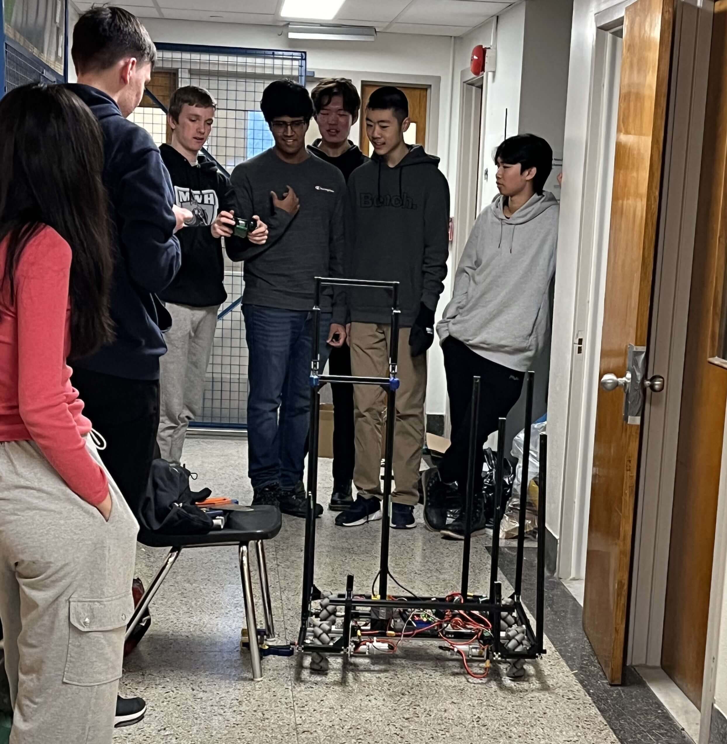 7 members of the robot team driving the robot onto a ramp.