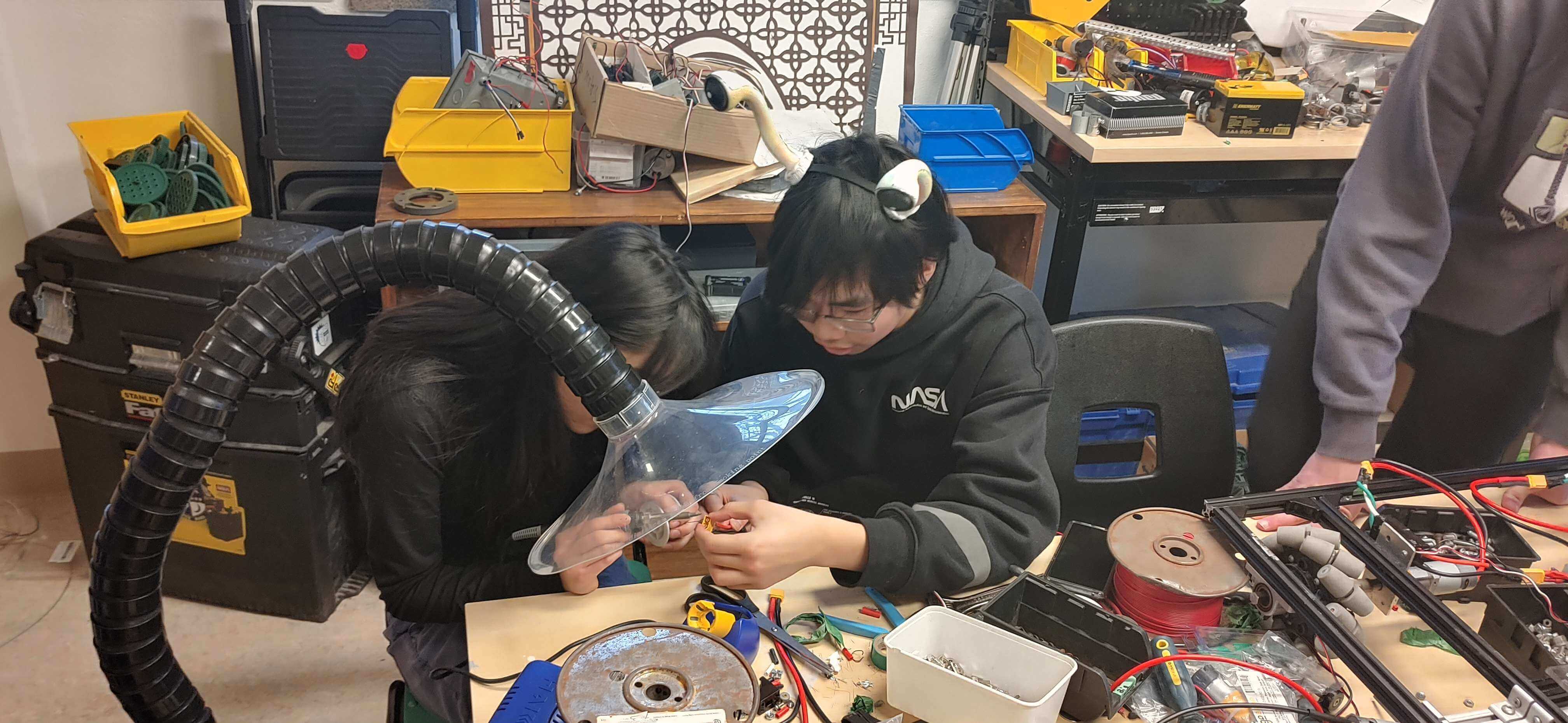 2 members of the robot team soldering motors.