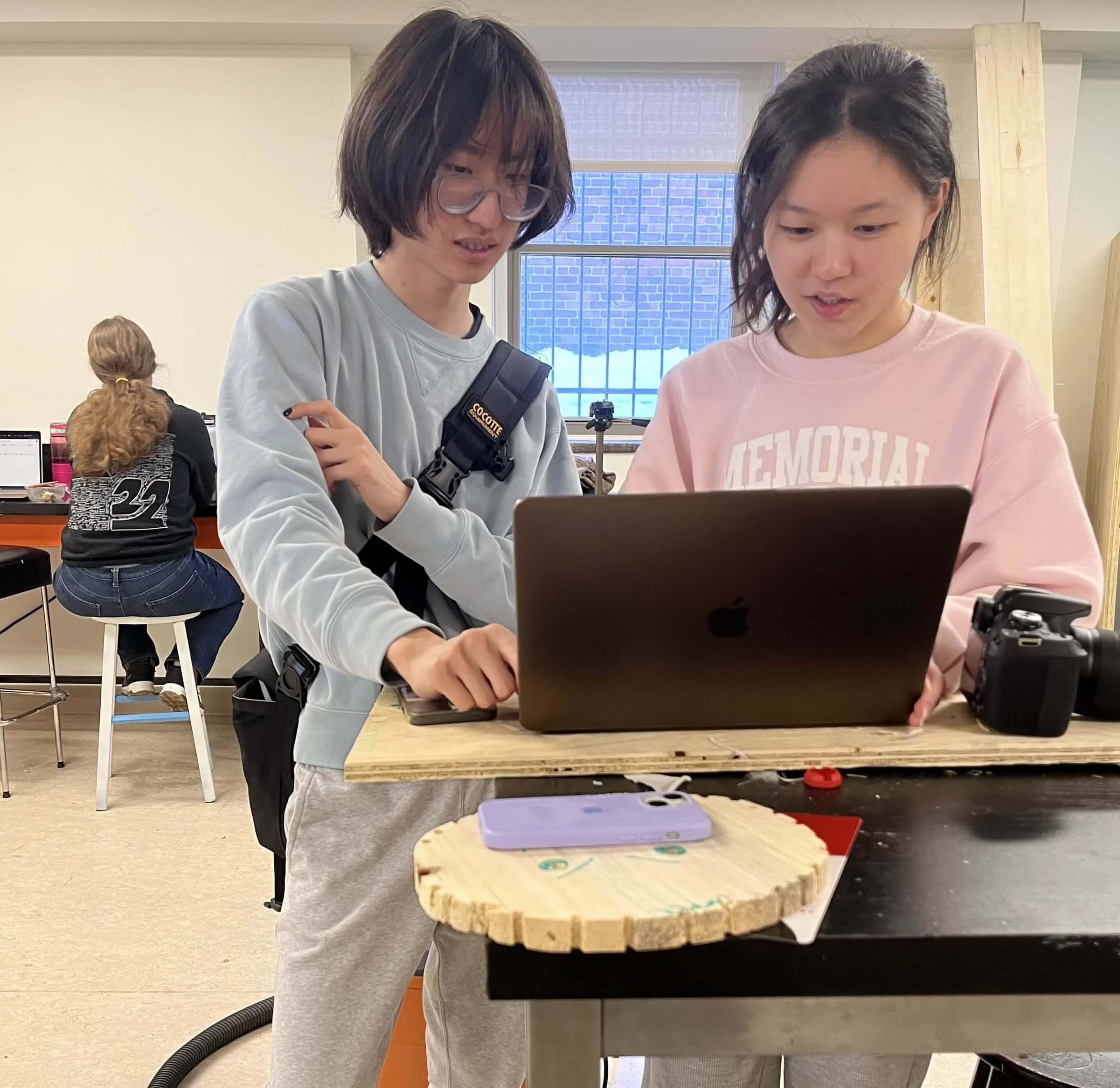 Two team members discussing behind a laptop.